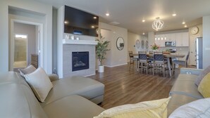 A modern living room with a fireplace, a dining area, and a kitchen. - Private Yard w/ Patio! Modern Commerce City Gem (Commerce City)