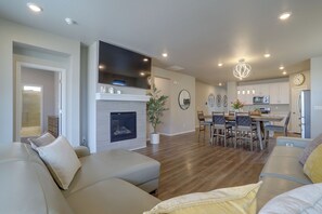 A modern living room with a fireplace, a dining area, and a kitchen. - Private Yard w/ Patio! Modern Commerce City Gem (Commerce City)