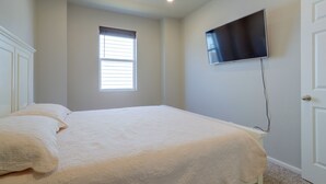 A bedroom with a bed, a window, a wall-mounted TV, and a door. - Private Yard w/ Patio! Modern Commerce City Gem (Commerce City)