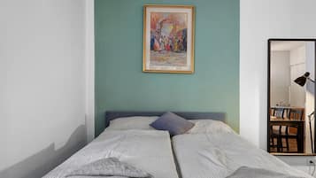 Una camera da letto con un letto, un quadro, uno specchio e una scrivania con una lampada.