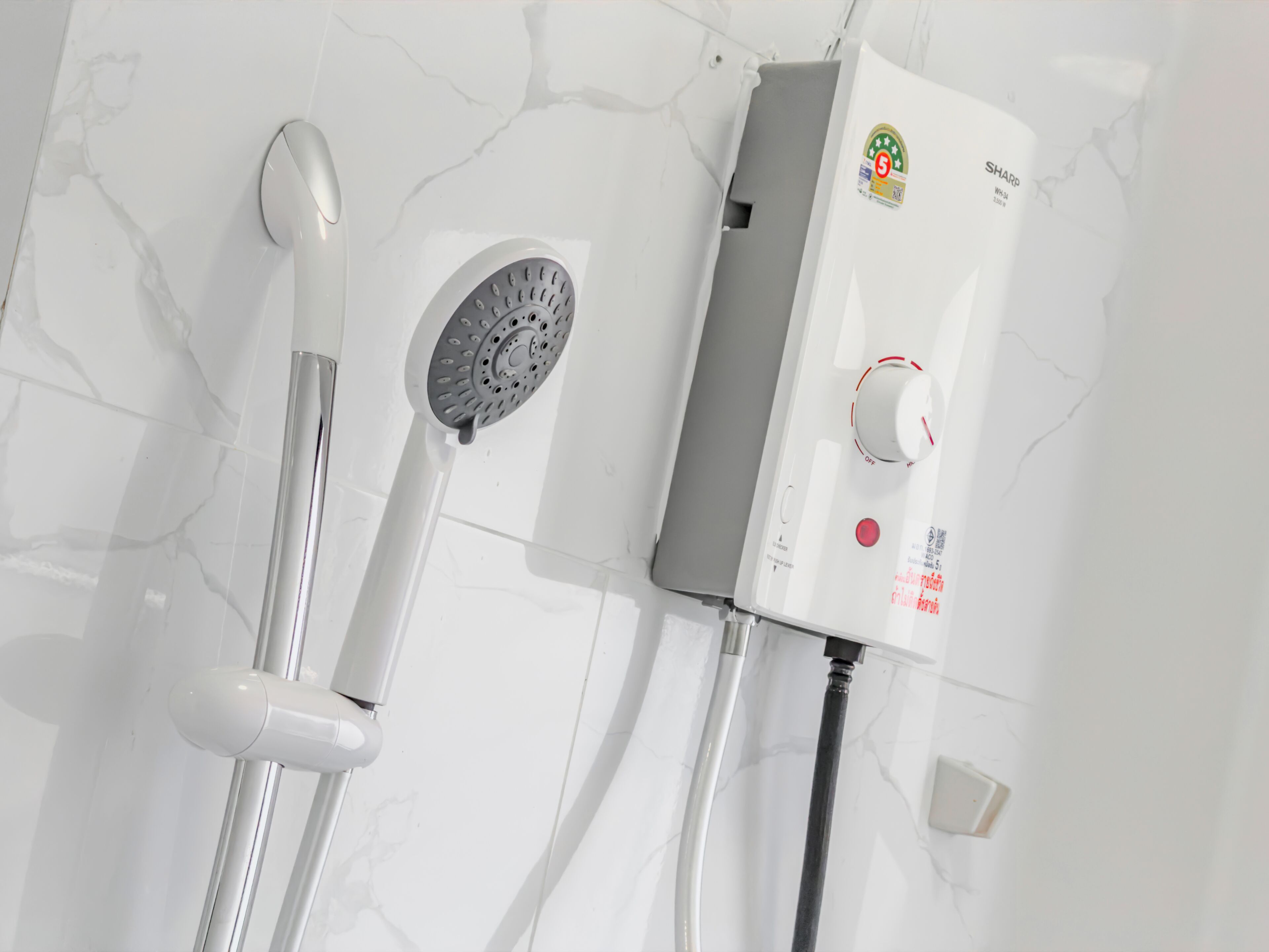 A modern bathroom with a white marble floor, a showerhead, and a water heater with a control panel.