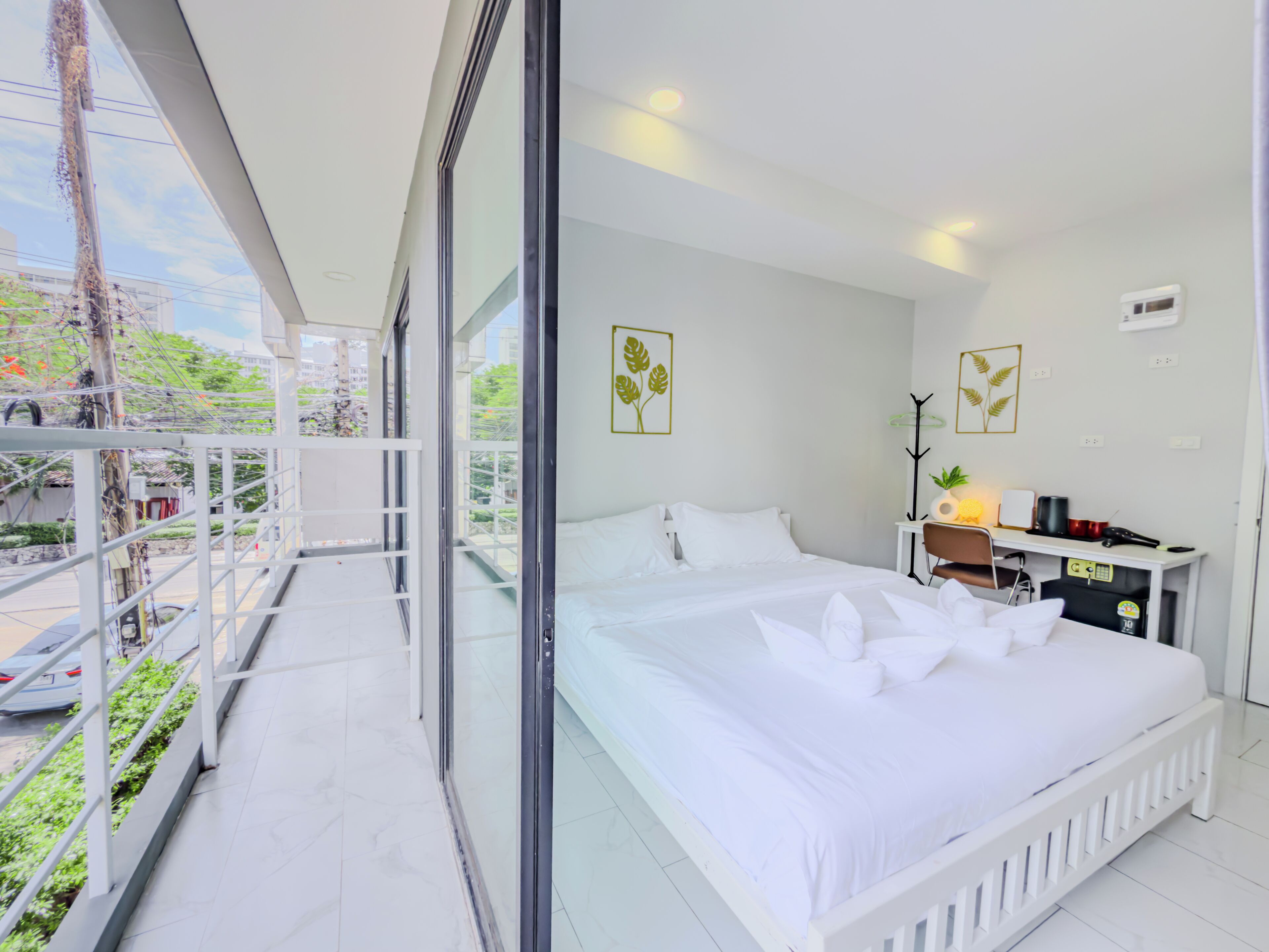 Una camera da letto moderna con un letto grande, una scrivania e un balcone con vista sulla città.