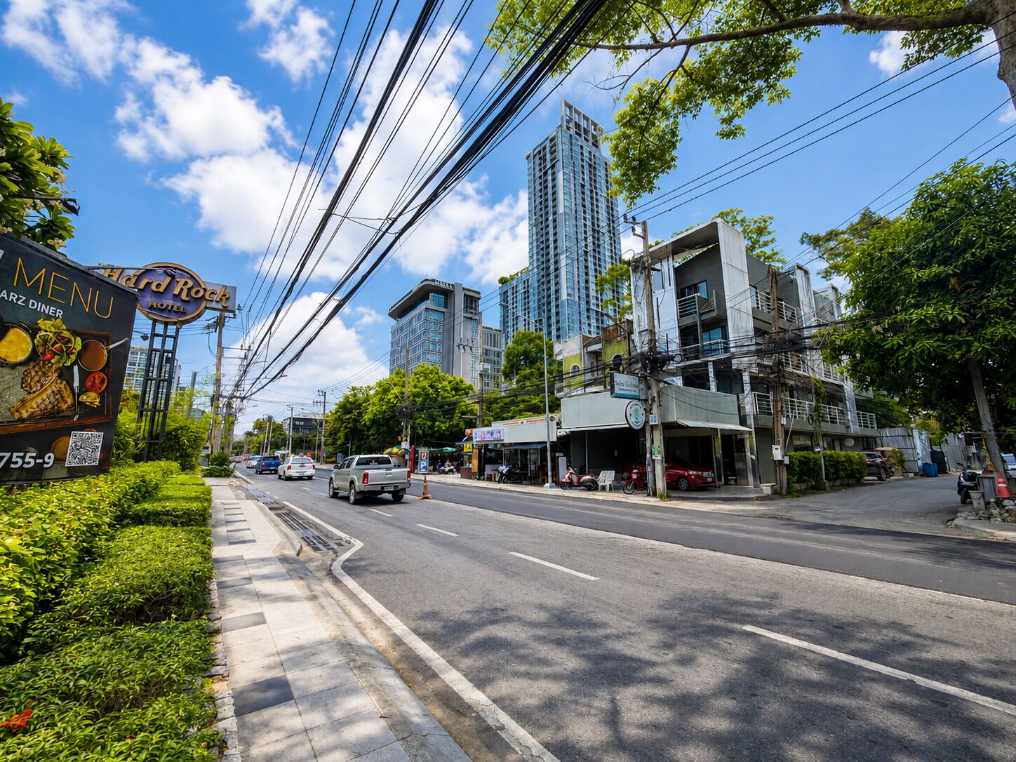 Vista de la calle con un letrero del Hard Rock Hotel, un restaurante llamado 'ARZ DINER' y un edificio con balcón.