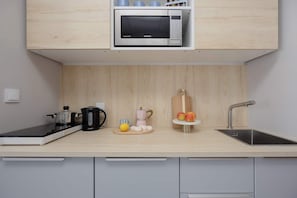 A modern kitchen with a microwave, kettle, and coffee maker on the countertop. - Stylish Studio with Balcony | Warsaw Center (Warszawa)
