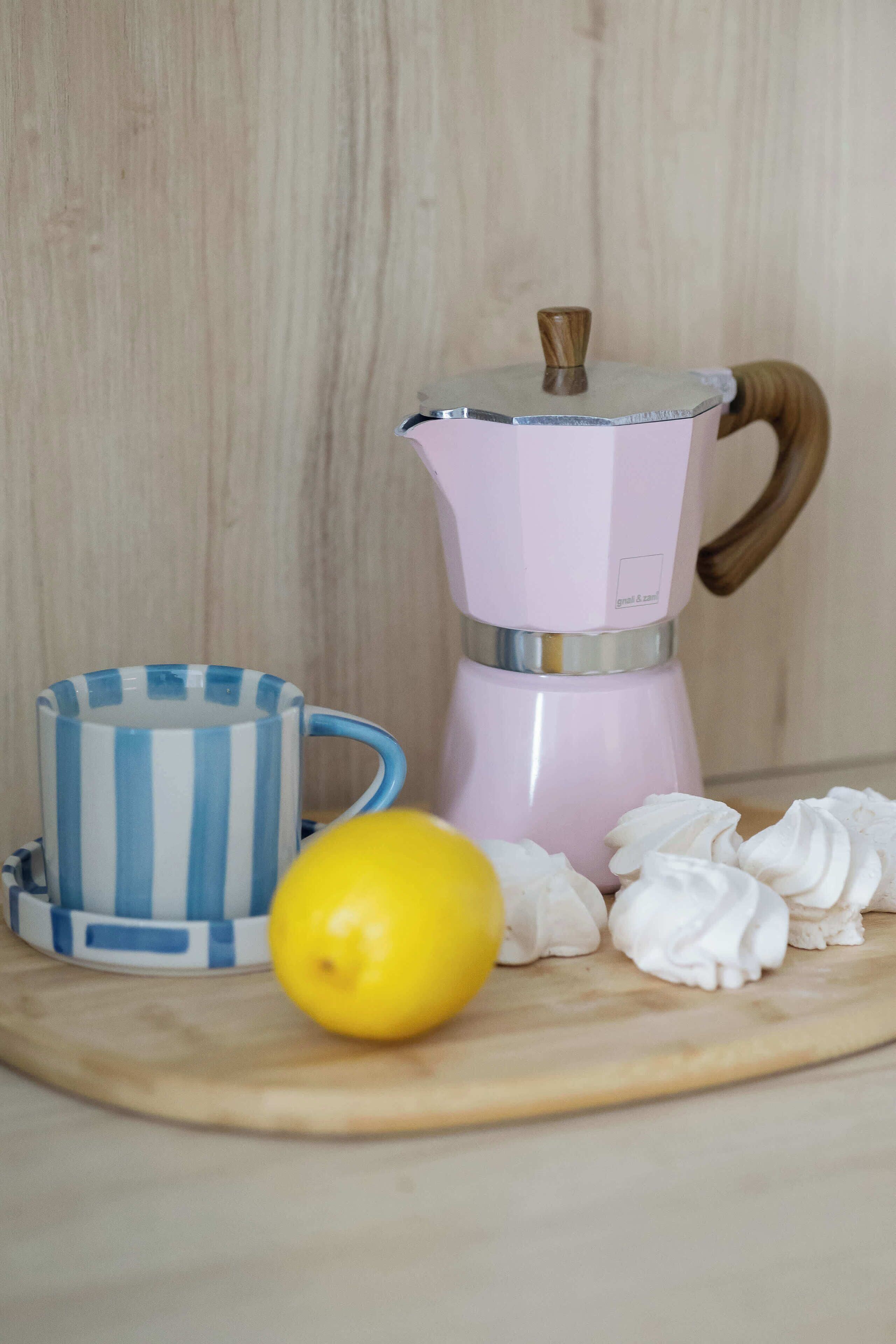Eine Küchenarbeitsplatte mit einer Kaffeemaschine, einer gestreiften Tasse und einer Zitrone.