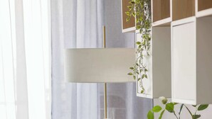 Una poltrona gialla con una coperta a quadri, un termosifone bianco e una pianta con fiori bianchi.