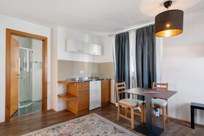 Una cucina compatta con zona pranzo, doccia e un'ampia finestra con tende.