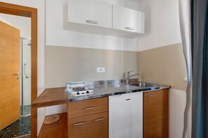 Une petite cuisine équipée comprenant une cuisinière intégrée, un évier et des placards de rangement.