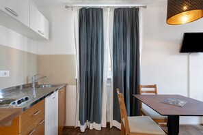 Cocina compacta con lavabo, armarios y comedor con mesa y sillas.