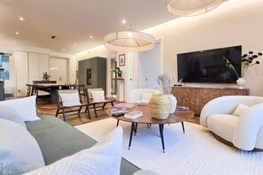 Ein modernes Wohnzimmer mit einer Couch, Sesseln, einem Couchtisch und einem Fernseher.