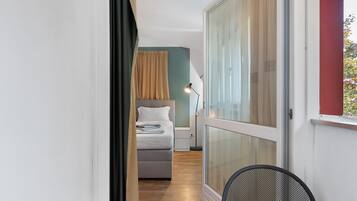 Un couloir étroit mène à une chambre qui contient un lit, un bureau et une chaise.