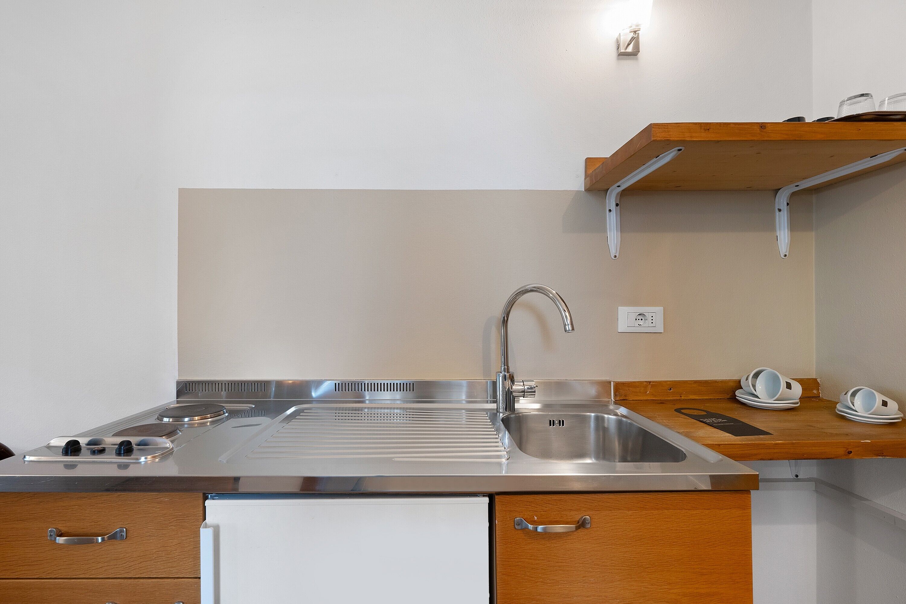 A modern kitchen with a stainless steel sink, a built-in stove, and wooden cabinets.