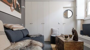 Uma sala de estar moderna com um sofá, um tapete macio, um baú de madeira e uma televisão.