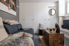 Ein modernes Wohnzimmer mit einer Couch, einem flauschigen Teppich, einer Holzablage und einem Fernseher.