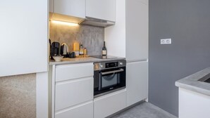 Uma cozinha moderna com armários brancos, forno embutido e bancada com diversos eletrodomésticos.