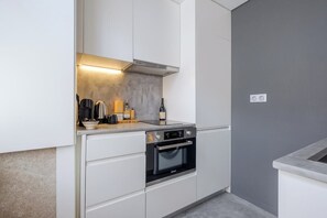 Eine moderne Küche mit weißen Schränken, einem eingebauten Backofen und einer Arbeitsplatte mit diversen Geräten.