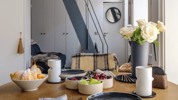 Uma mesa de jantar posta com pratos, tigelas e um vaso de flores.