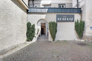 Un ingresso di un edificio con un cartello che riporta 'Die Residenz' e un segnale che indica un'area di parcheggio.
