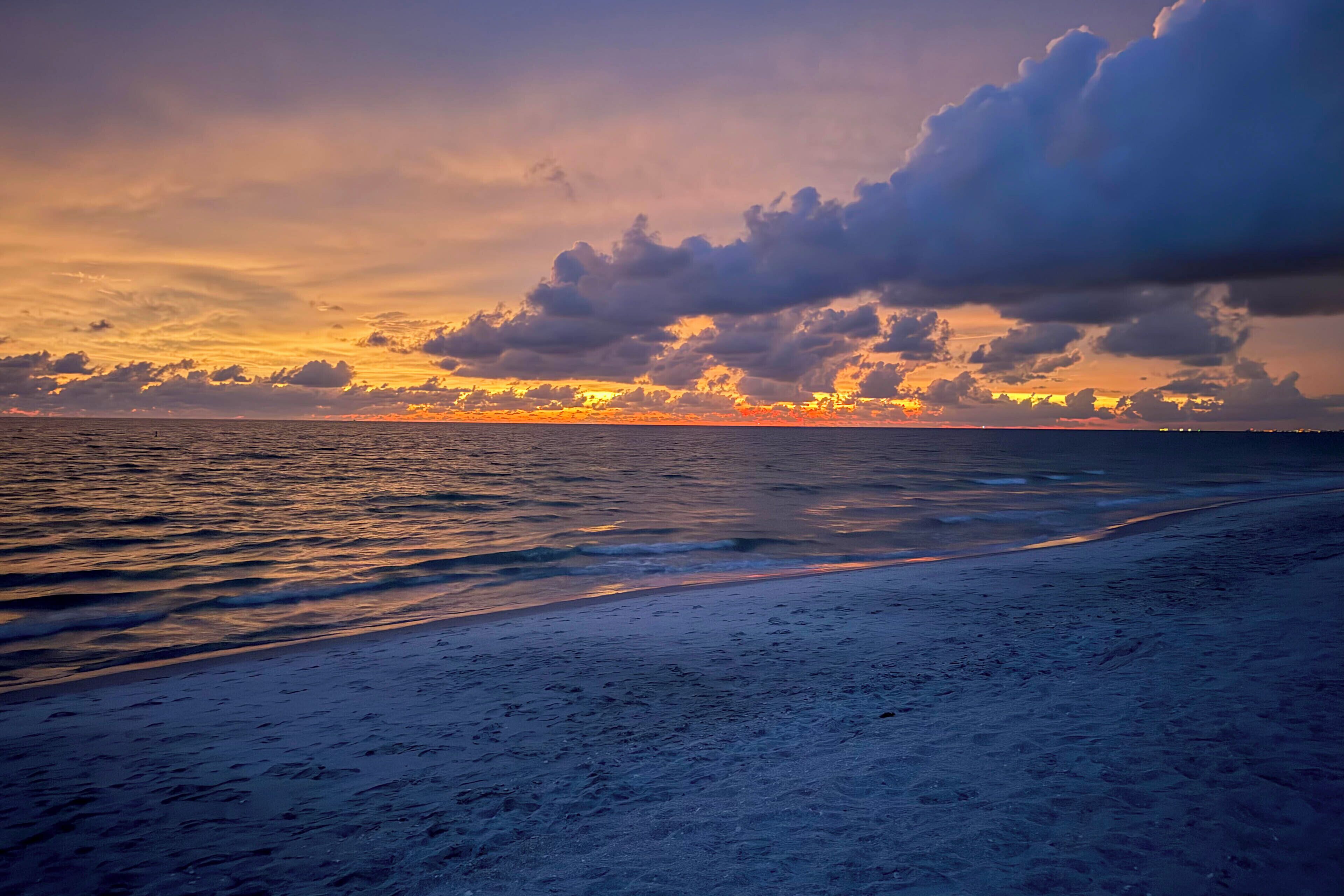 A beach with a sunset and ocean waves.