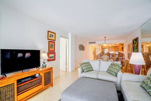 A living room with a television, sofa, and a dining area in the background. - On the Beach Condo for the Ultimate in Relaxation (Bonita Springs)