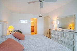 Ein Schlafzimmer mit Bett, Nachttischlampen, einem Schminktisch, einem Spiegel und einem Deckenventilator.