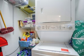 A laundry area with a washing machine, a drying machine, and various cleaning supplies. - On the Beach Condo for the Ultimate in Relaxation (Bonita Springs)