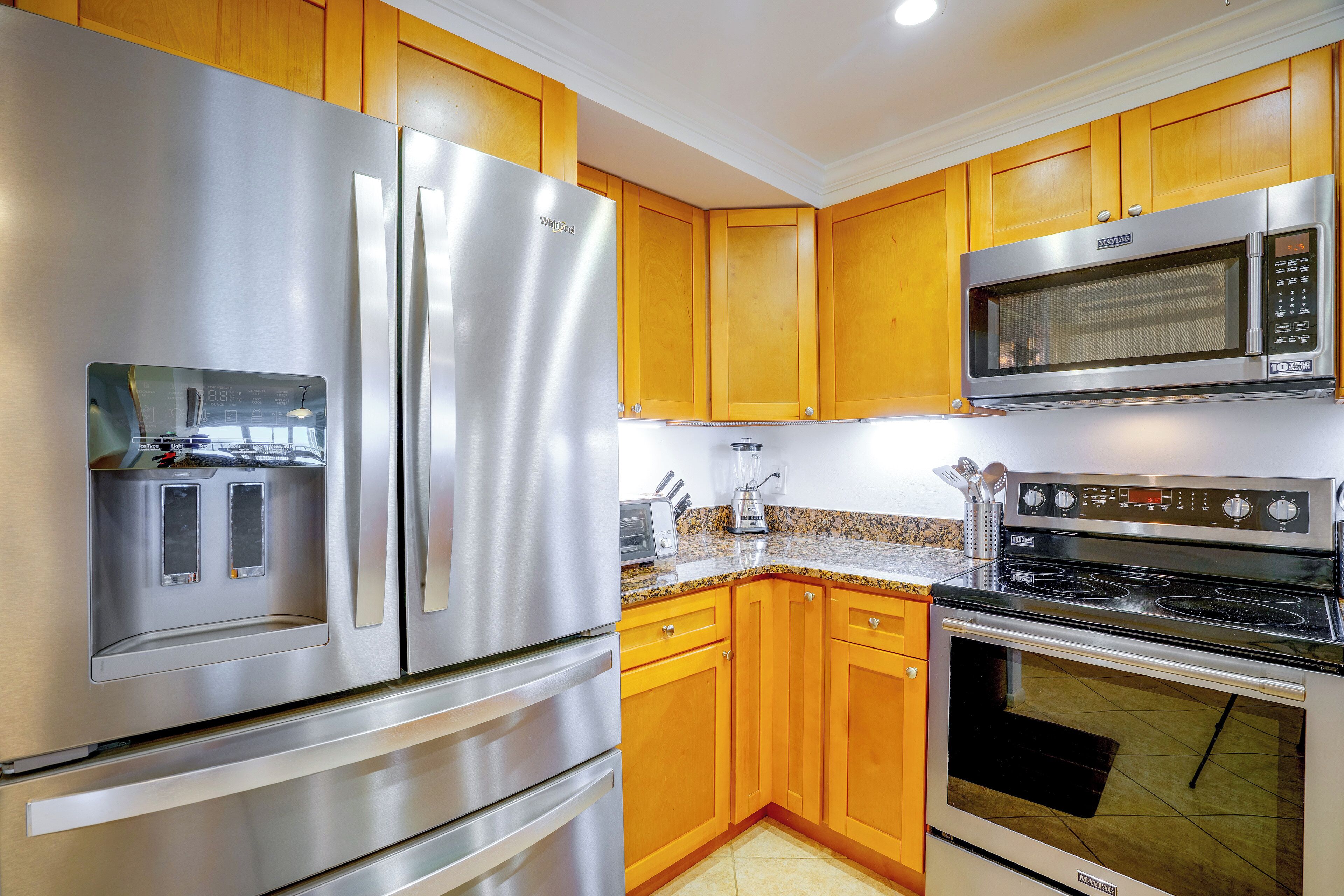 Una cocina moderna con electrodomésticos de acero inoxidable, armarios de madera y encimeras de granito.