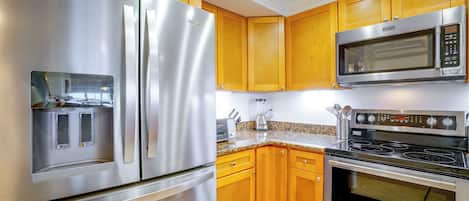 Una cocina moderna con electrodomésticos de acero inoxidable, armarios de madera y encimeras de granito.