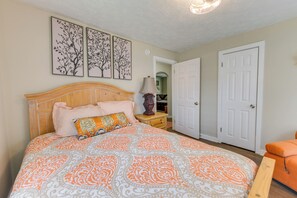 Une chambre à coucher avec un grand lit, une table de chevet, une lampe et une porte.