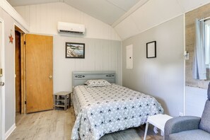 A bedroom with a bed, a chair, a small table, a wooden door, and an air conditioning unit. - Family Home + Guest House! Near Fishing, Boat Ramp (West Orange)