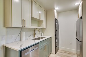 A kitchen with a stainless steel dishwasher, a sink with a marble countertop, and a built-in oven. - Mtn-View Deck w/ Grill! Modern Medicine Park Cabin (Medicine Park)