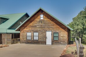 A log cabin with a gabled roof, a front door, and a small window above the door. - Mtn-View Deck w/ Grill! Modern Medicine Park Cabin (Medicine Park)