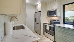 Una cucina moderna con frigorifero in acciaio inox, forno integrato e microonde.