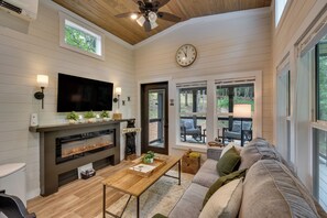 Ein modernes Wohnzimmer mit Kamin, Fernseher und Wanduhr.