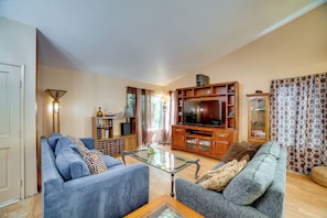 A living room with a sofa, a glass coffee table, and a television. - Near Golf & Buzzers Baseball! Ontario Ranch Home (Ontario)