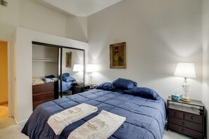 Ein Schlafzimmer mit einem Bett, einem Schminktisch, einem Spiegel, einem Gemälde und Nachttischlampen.