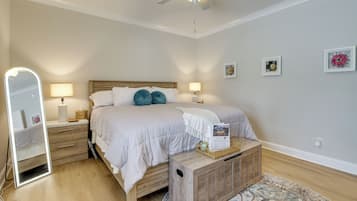 Un dormitorio con cama, mesitas de noche, un espejo y un ventilador de techo.