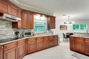 A kitchen with wooden cabinets, a built-in microwave, and a tiled backsplash. - Heated Pool & Lanai Cookouts! Cape Coral Getaway (Cape Coral)