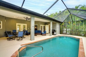 An indoor swimming pool with a glass ceiling, surrounded by seating areas and a view of tropical foliage. - Heated Pool & Lanai Cookouts! Cape Coral Getaway (Cape Coral)