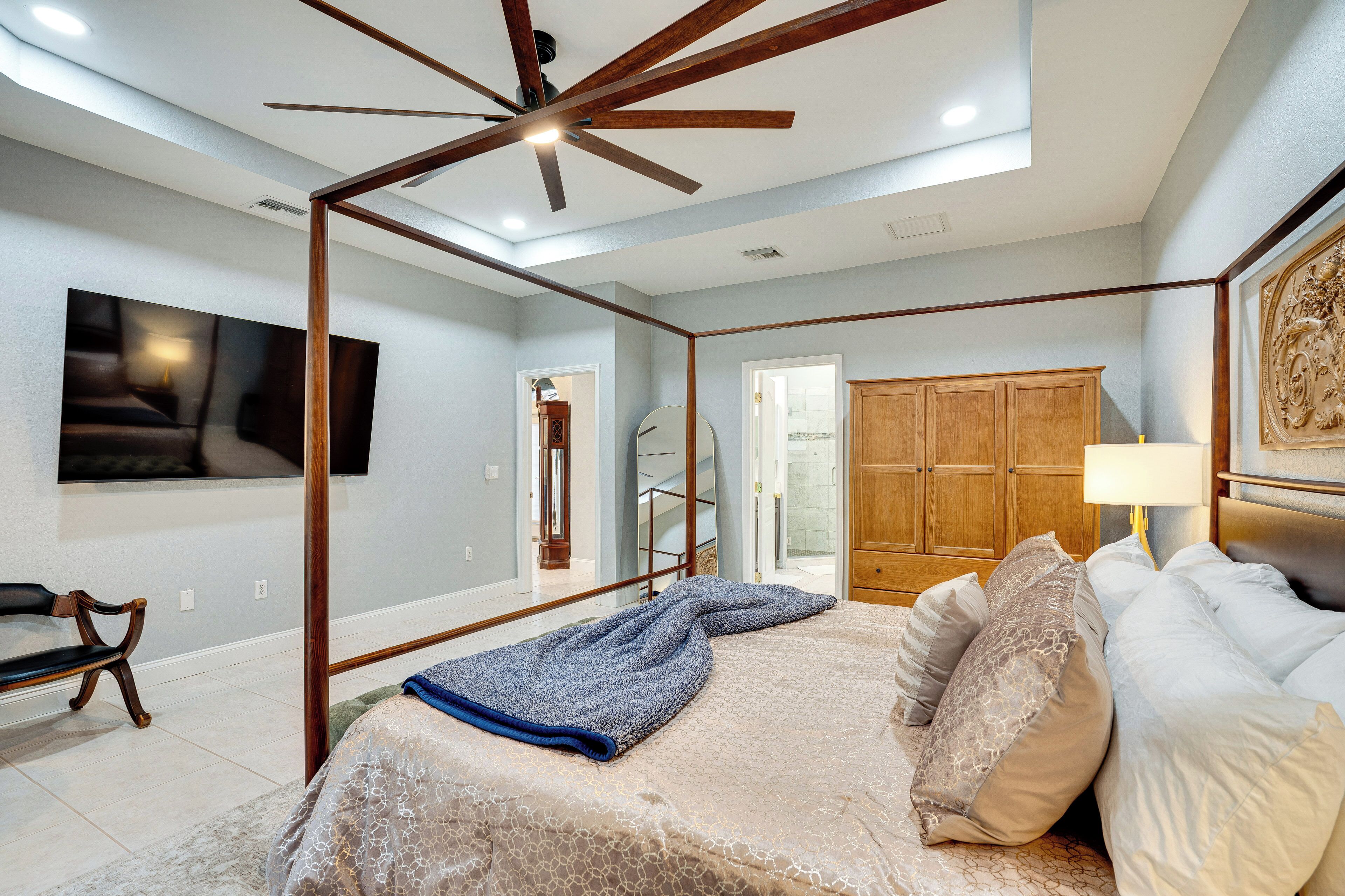 A bedroom with a bed, a ceiling fan, a TV, and a wardrobe.