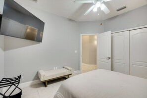 Une chambre à coucher comprenant un lit, un banc, une chaise, une armoire et un ventilateur de plafond.