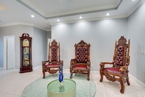 A room with three ornate wooden chairs, a glass coffee table, and a wall-mounted clock. - Heated Pool & Lanai Cookouts! Cape Coral Getaway (Cape Coral)