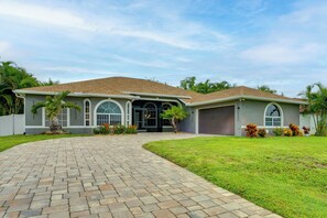 A single-story house with a paved driveway leading to a garage. - Heated Pool & Lanai Cookouts! Cape Coral Getaway (Cape Coral)