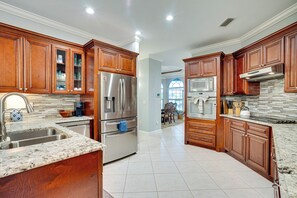 A spacious kitchen with wooden cabinets, stainless steel appliances, and a granite countertop. - Heated Pool & Lanai Cookouts! Cape Coral Getaway (Cape Coral)