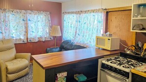 A compact kitchen with a stove, microwave, and a small dining area with a chair and table. - Pet-Friendly Rustic Cabin Steps from Lake Chetek (Chetek)