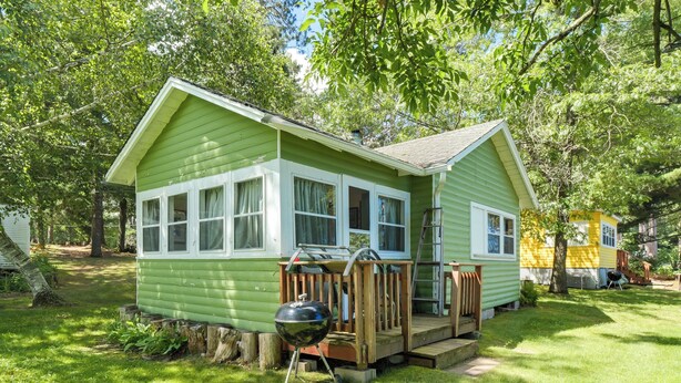 A small, single-story house with a porch and a barbecue grill in front. - Pet-Friendly Rustic Cabin Steps from Lake Chetek (Chetek)