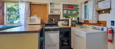A compact kitchen with a microwave, stove, oven, and sink.