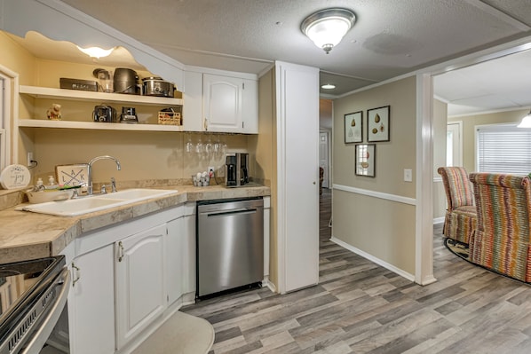 A kitchen with white cabinets, a dishwasher, and a countertop with various appliances.