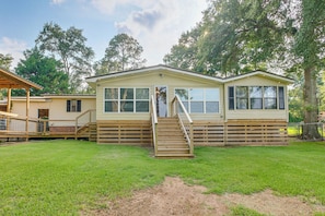A single-story mobile home with a front porch and a small deck.