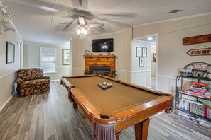 A pool table with a fireplace, a television, and a sign that says 'FISHIN''.
